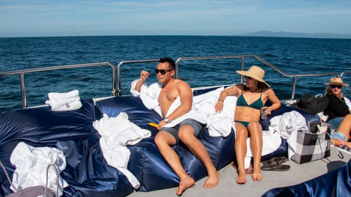 Huéspedes descansando con toallas en los camastros de la cubierta de un catamarán privado en Bahía de Banderas, Puerto Vallarta
