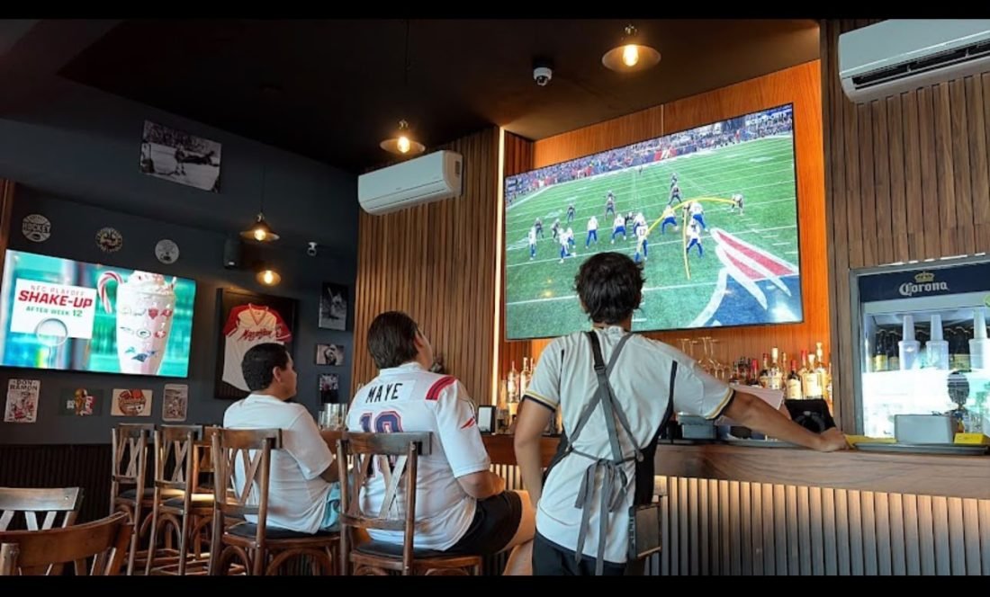 Clientes en la barra de Guicho's Sports Bar viendo un partido de NFL en pantalla grande en Nuevo Vallarta
