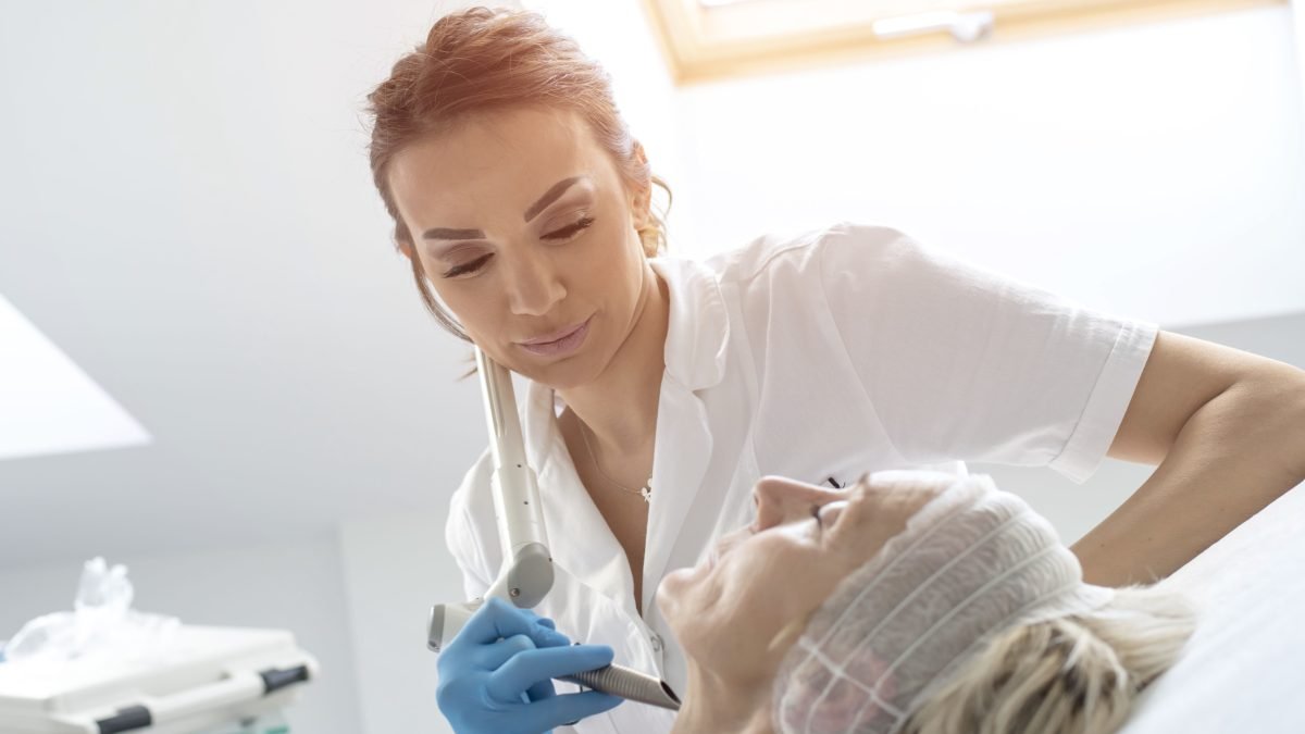 Sesión de láser facial con paciente y técnico usando gafas de protección