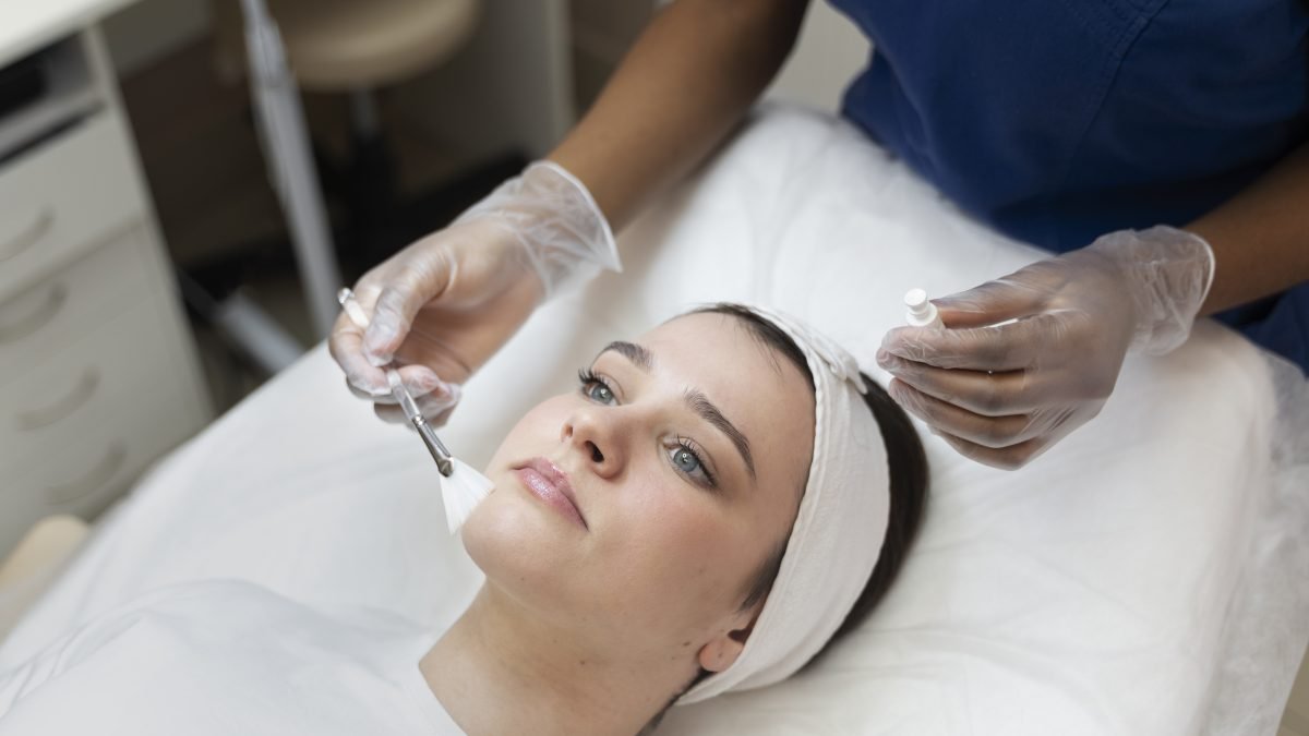 Profesional con guantes acercando una pluma de microneedling a la mejilla de una paciente